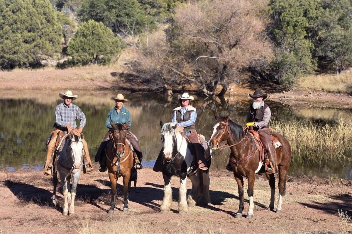 Tourists riding horses in cowboy hats
