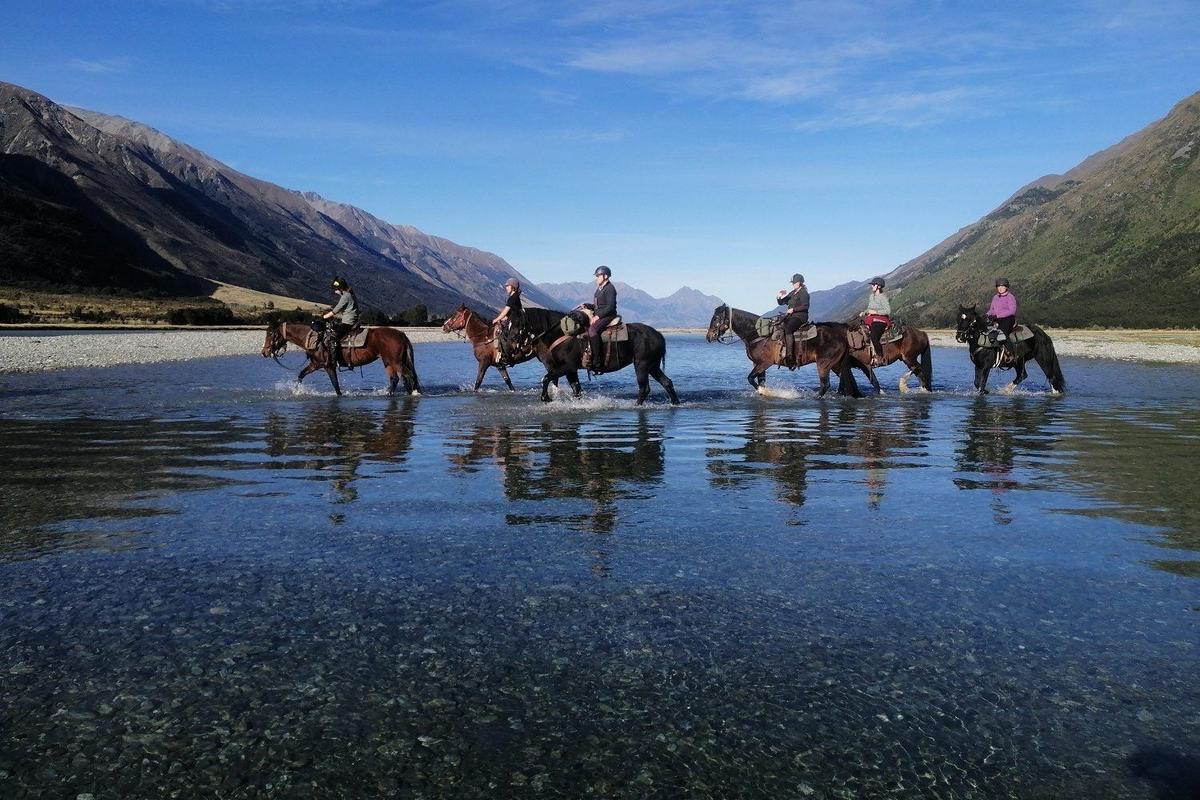 Group of tourists riding horses on Lake Ohau