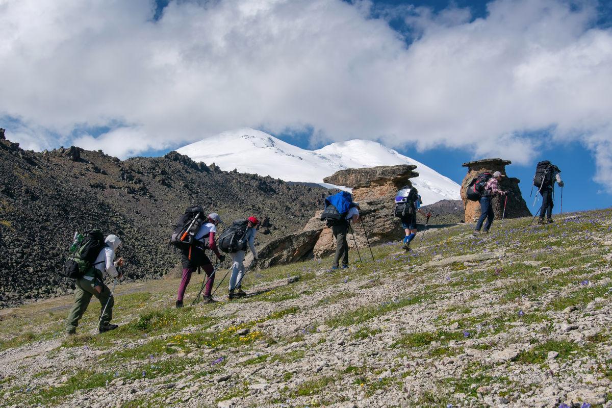 Eine Gruppe von Touristen macht einen Aufstieg vor dem Hintergrund des Berges Elbrus