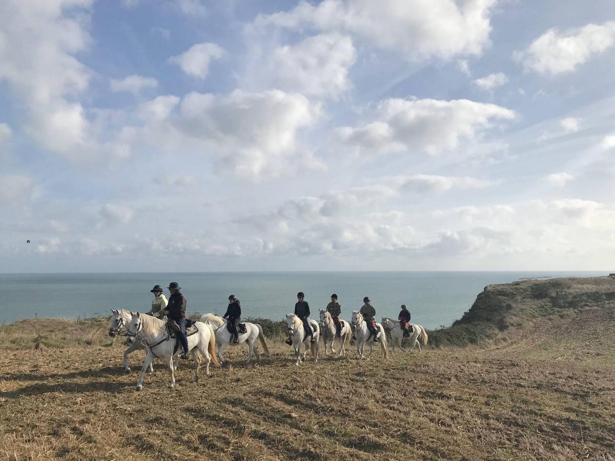 A group of people riding horses on the Normandy coast