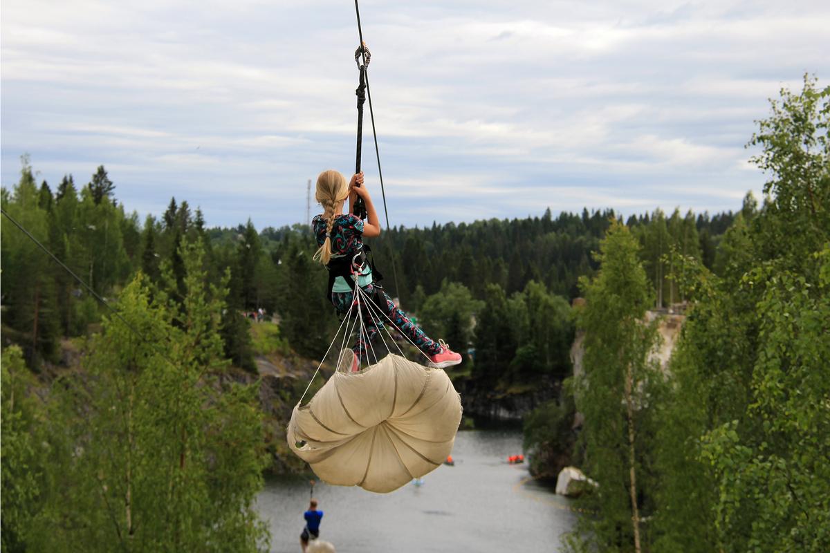 Девочка спускается на троллее в горном парке Рускеала