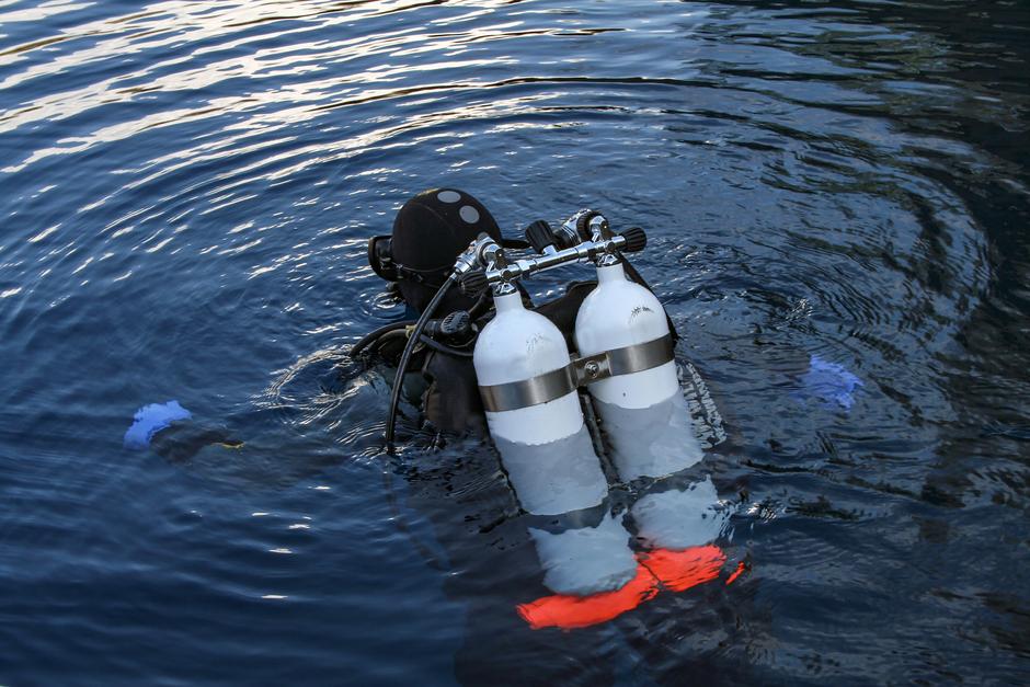 Дайвер погружается в темную воду глубокого озера